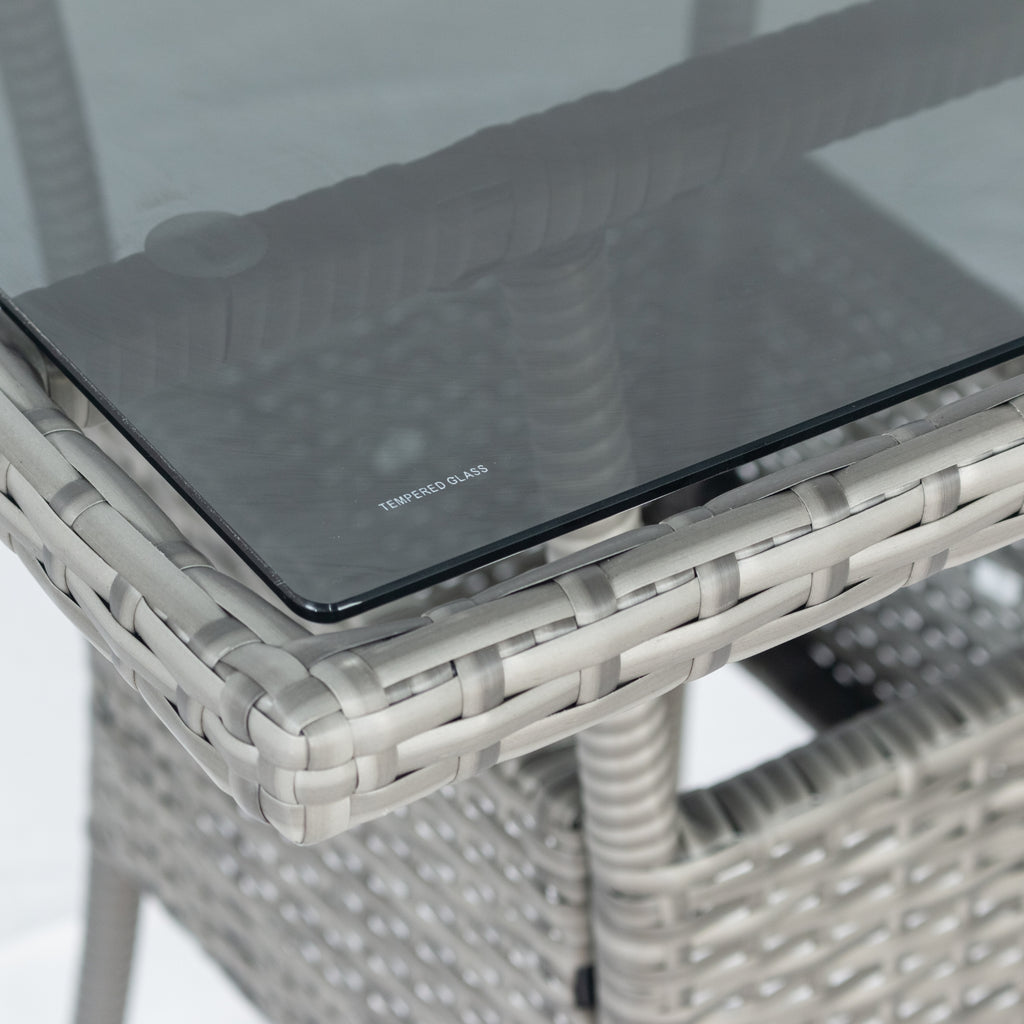 Square glass-top table with grey wicker weave frame and dark glass center.