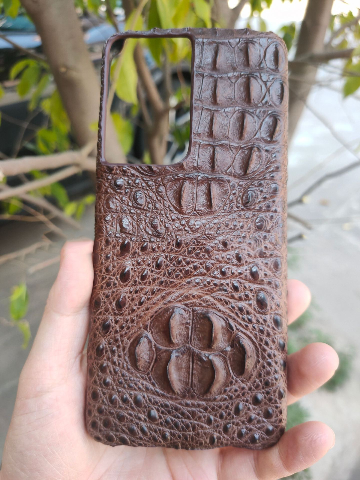 Brown crocodile leather phone case with embossed crocodile face detail and camera cutout