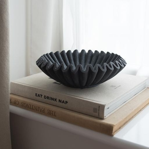 Dark fluted scallop decorative bowl with lotus-leaf ridged edge on books