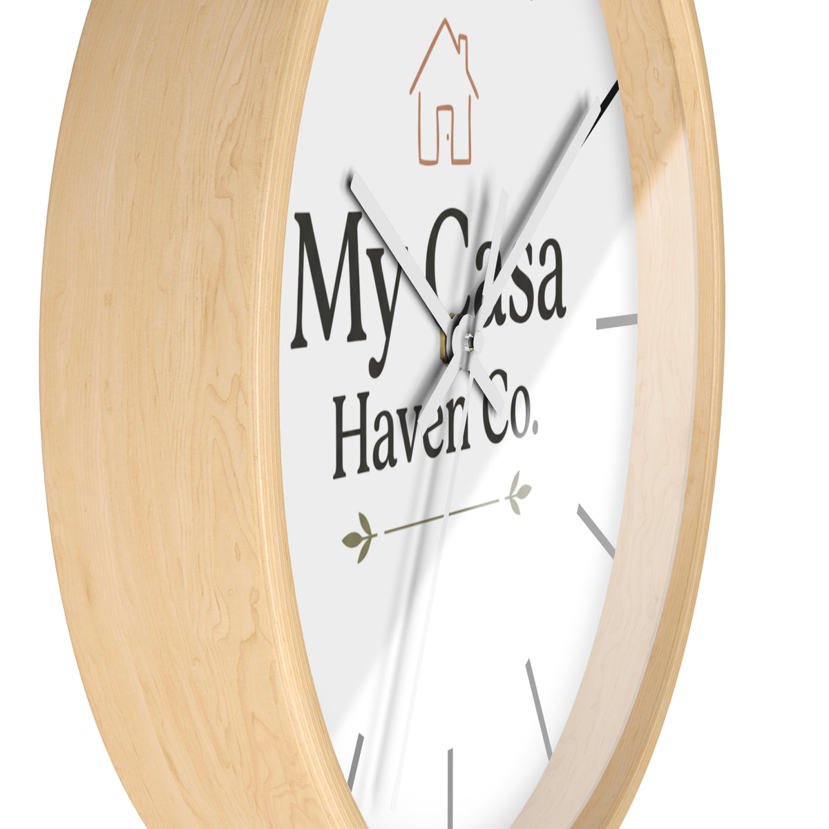 Round wall clock with light wood frame and white dial, white hands and logo text.