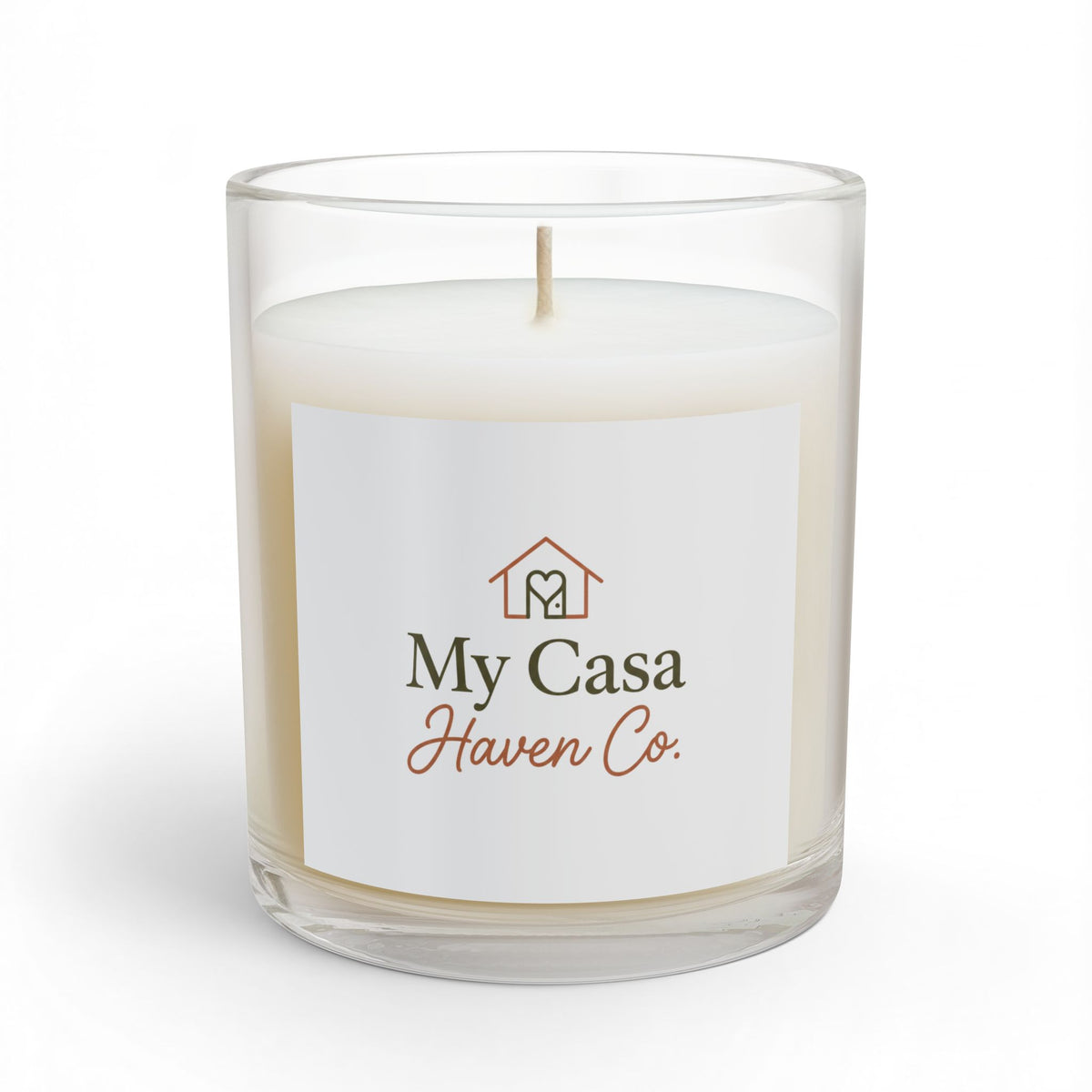 Glass candle in clear jar with white wax and lit wick, printed front label