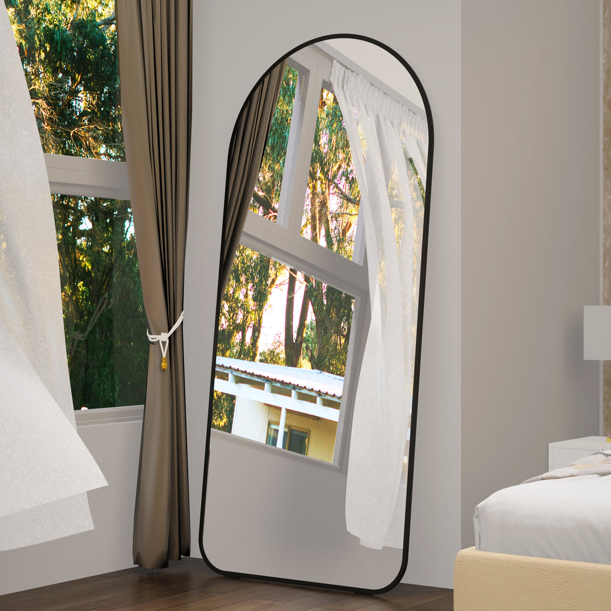 Full-length arched floor mirror with black frame leaning on the floor.