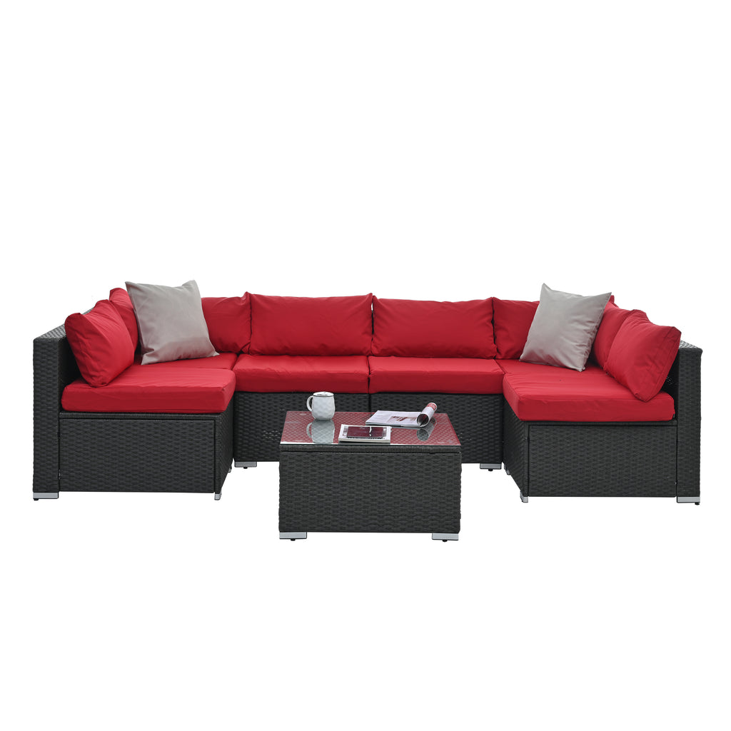 Dark gray woven outdoor corner sofa set with red cushions and glass-topped center table
