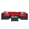 Dark gray woven outdoor corner sofa set with red cushions and glass-topped center table
