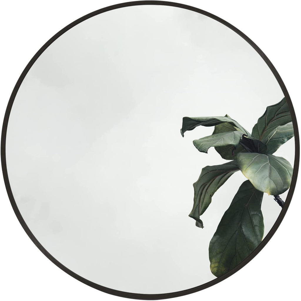 Round mirror with black rim and reflective glass, leafy plant reflection visible