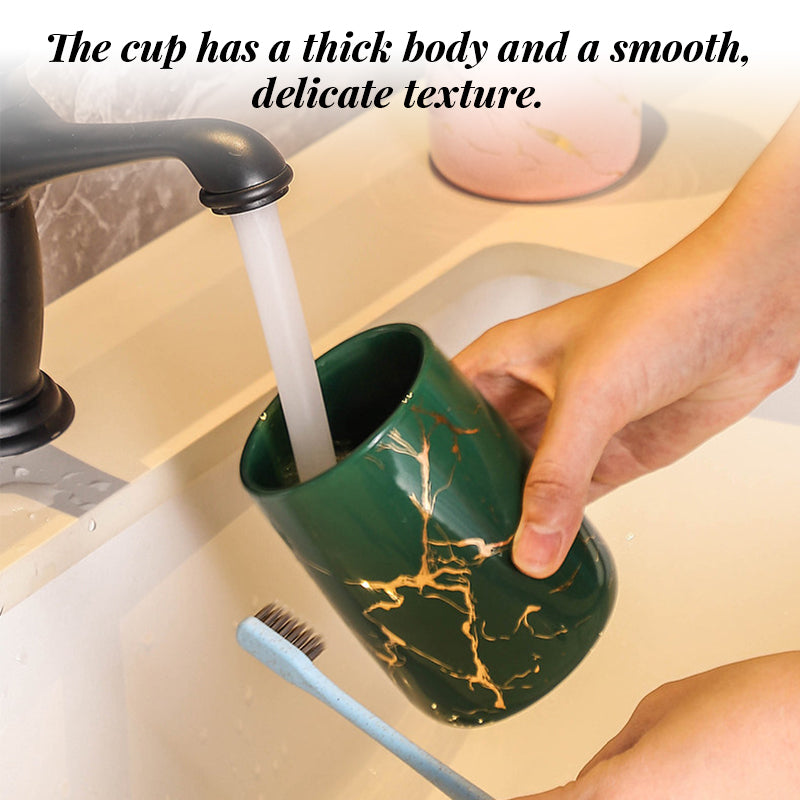 Hand holding a green ceramic cup with gold marble veining, glossy exterior