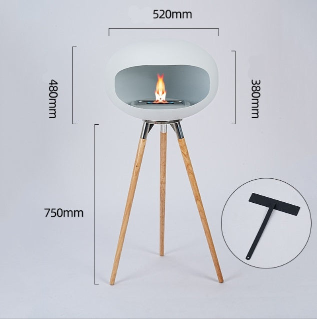 Light gray round ethanol fireplace bowl on three tall wood legs, flame visible in center.
