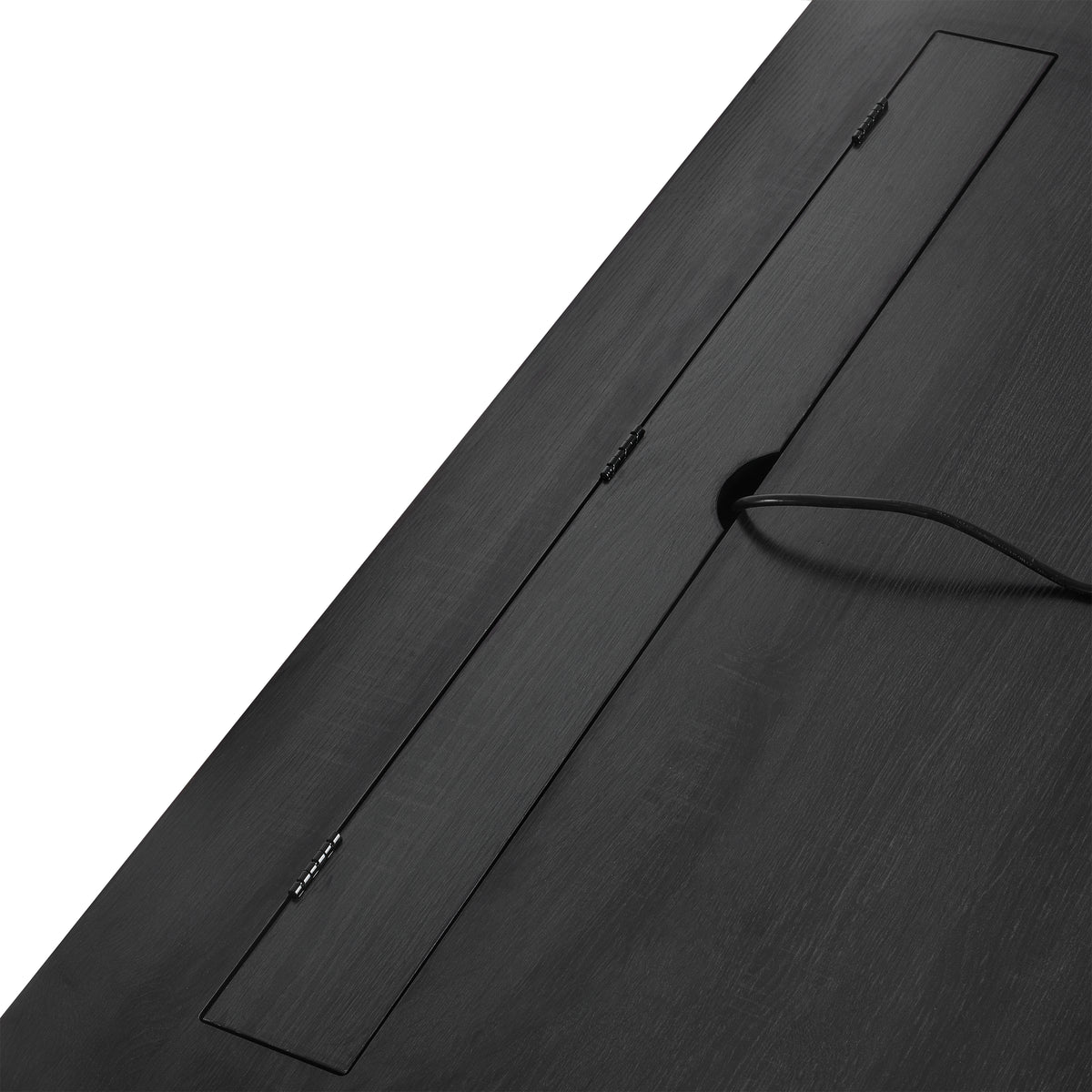 Black desk with concealed cable pass-through opening and black cord on the tabletop.