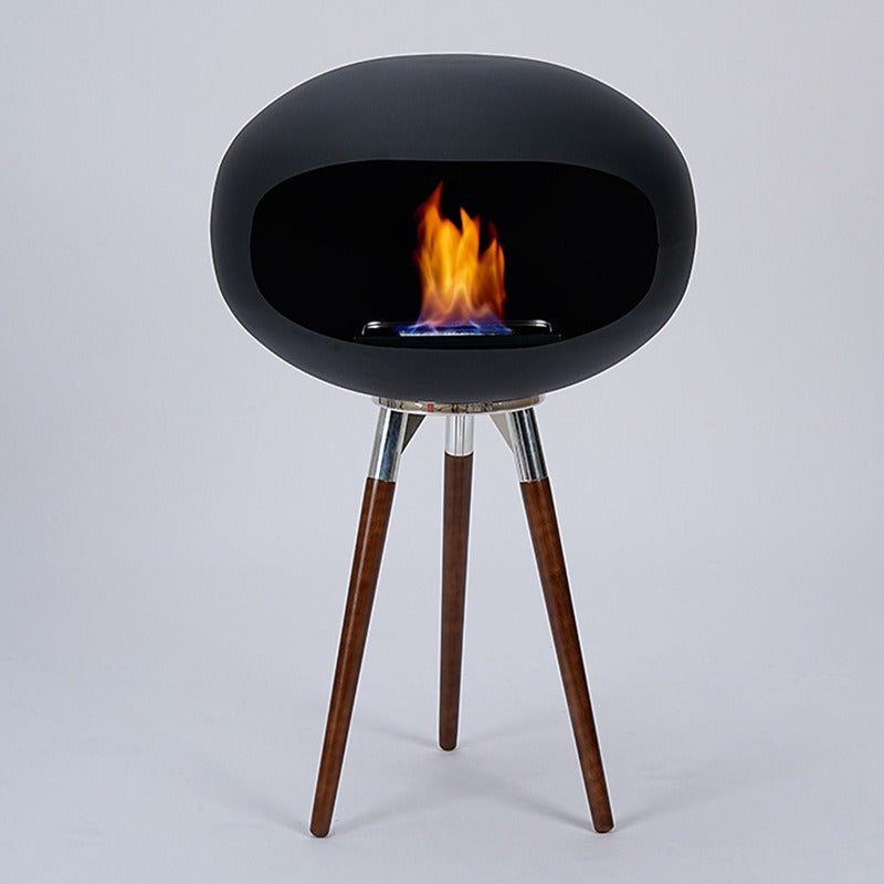Black ethanol fire bowl with flame, supported by three wood tripod legs with chrome collars.
