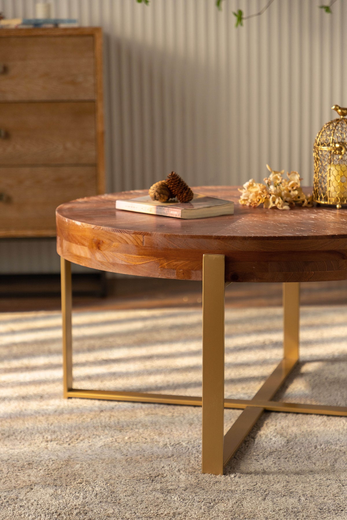 Round coffee table with gold cross legs and fir wood top surface with decor