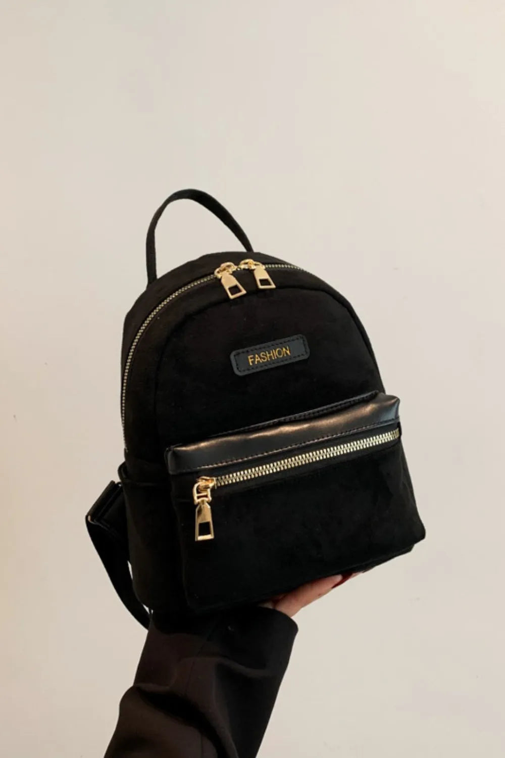 Suede black mini backpack with top handle, adjustable shoulder strap, and front zipper