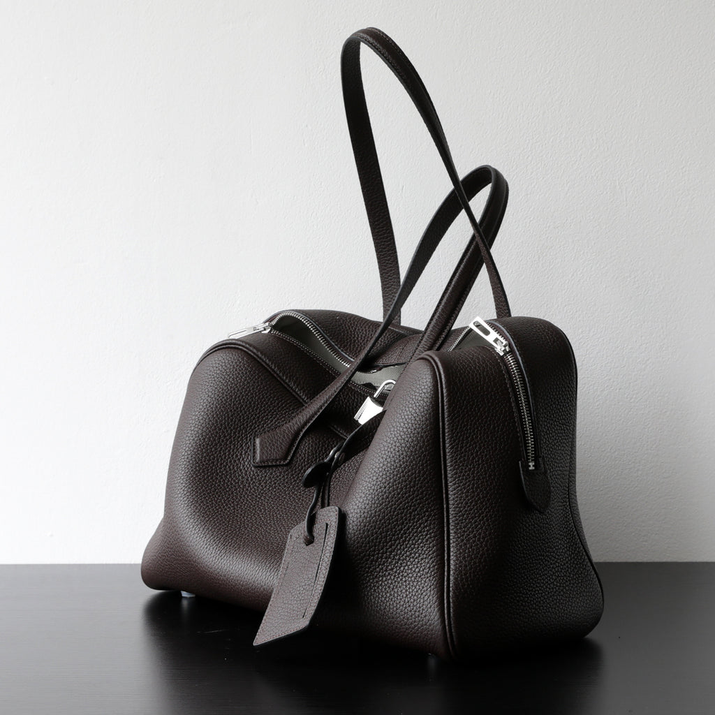 Dark brown leather-look crossbody bag with top handles, front zip, and detachable strap