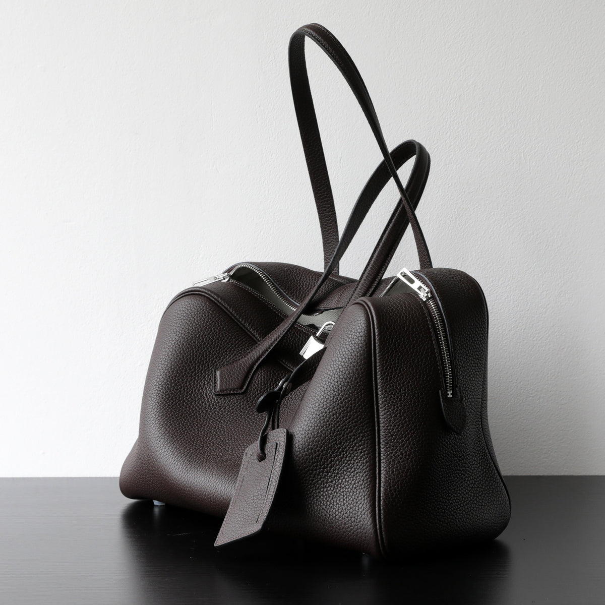 Dark brown leather-look crossbody bag with top handles, front zip, and detachable strap