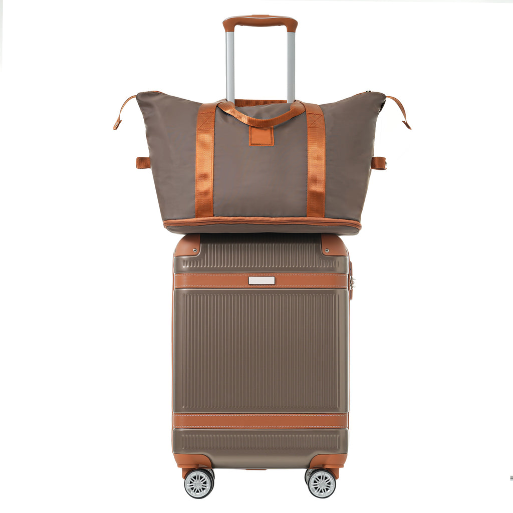 Coppery carry-on suitcase topped with a gray duffel bag and brown carrying handles