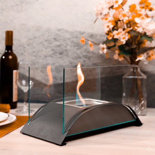 Black tabletop alcohol fireplace with clear glass windscreen and visible flame