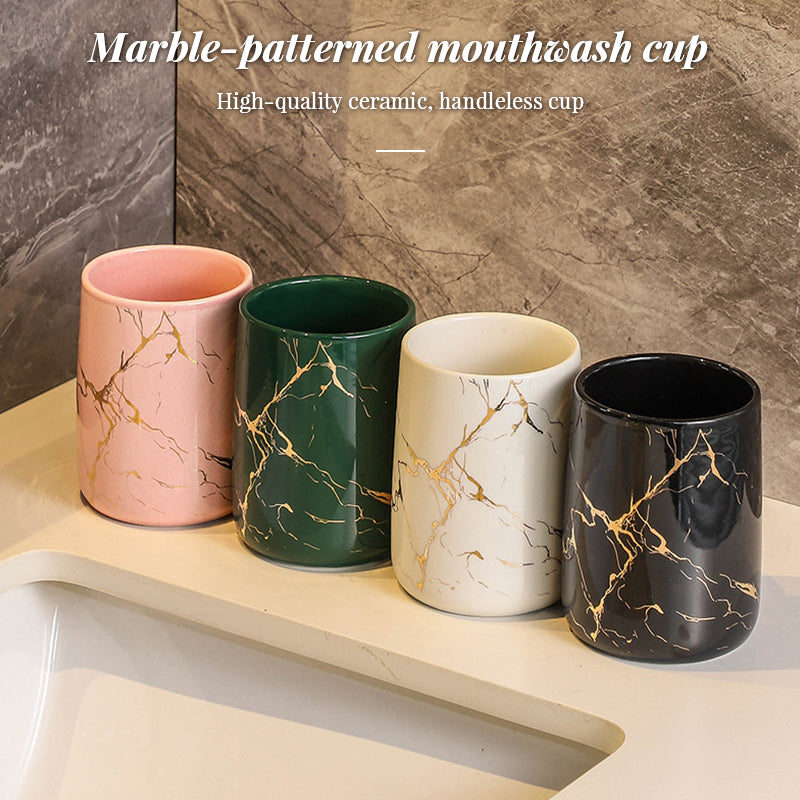 Set of four ceramic mouthwash cups in pink, green, cream, and black with gold marbling