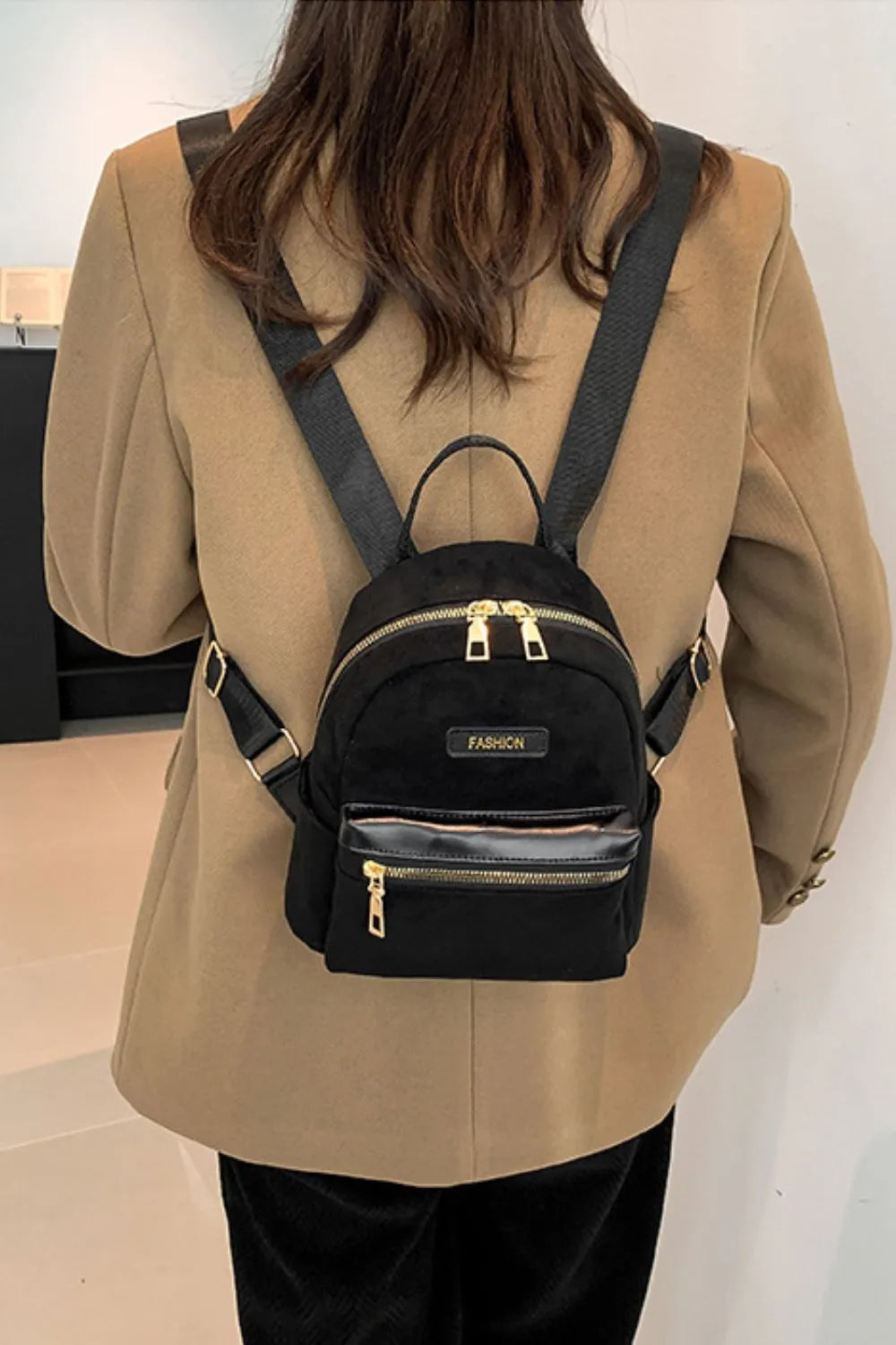 Suede black mini backpack worn on model, back view with front zipper pocket