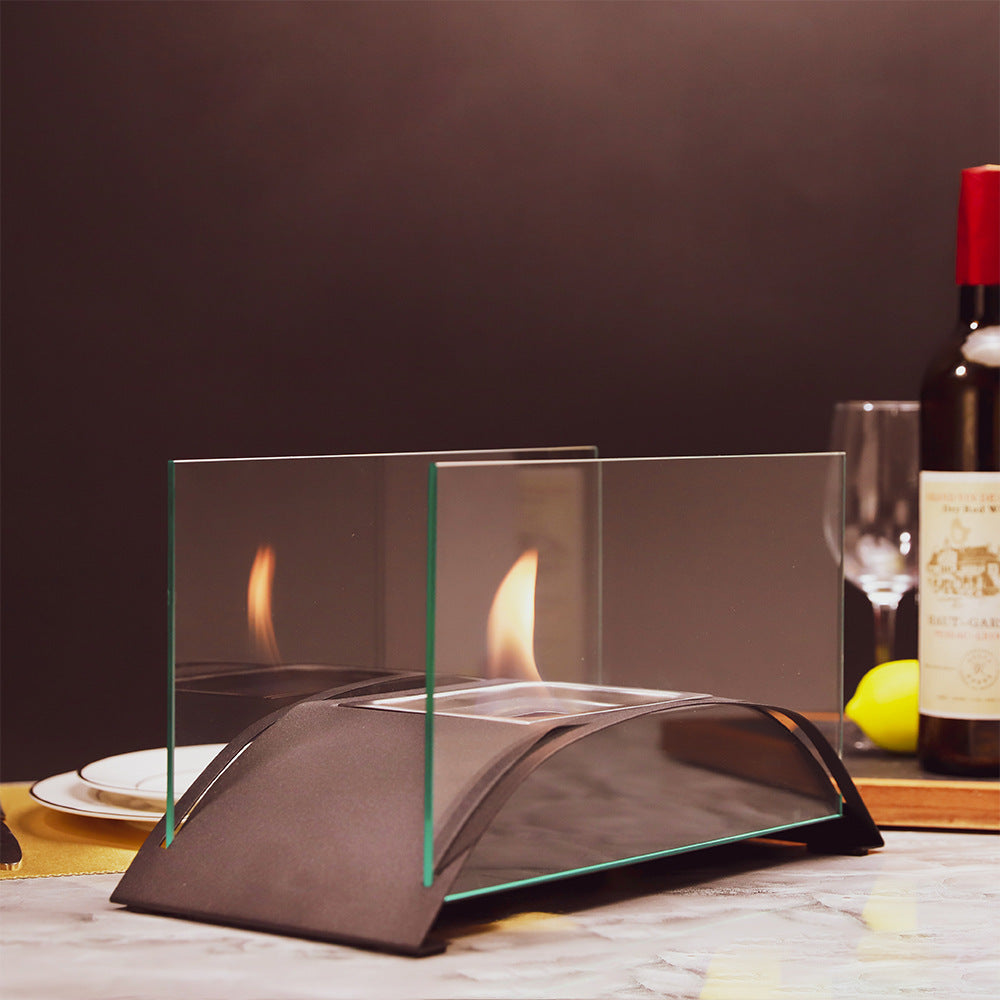 Black tabletop alcohol fireplace with clear glass windscreen and open flame