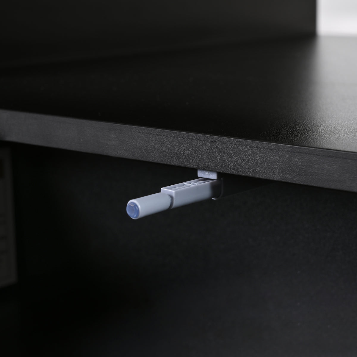 Drawer hinge mechanism under black coffee table cabinet, with push rod detail