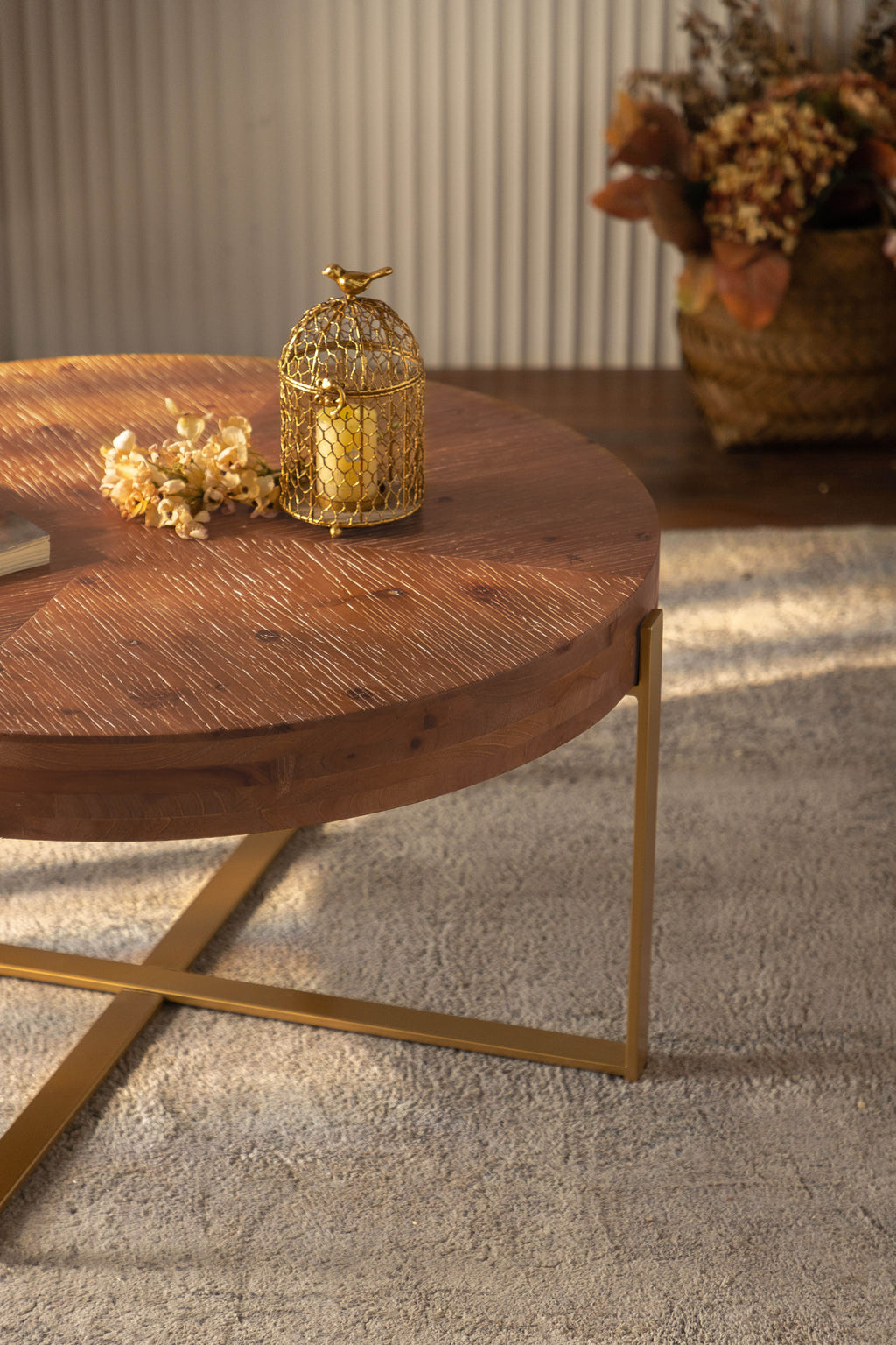 Round fir wood coffee table with gold-toned cross legs and circular tabletop