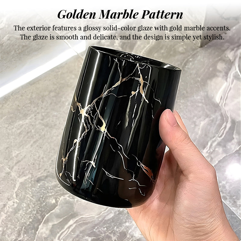 Hand holding a black glossy ceramic cup with golden marble pattern and round rim
