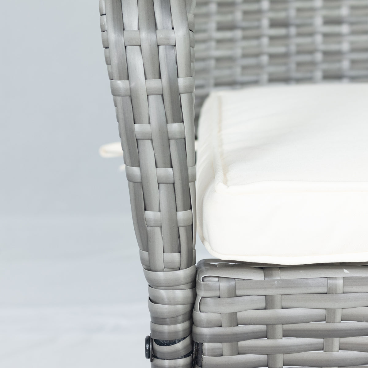 Gray wicker chair arm and woven seat with white cushion