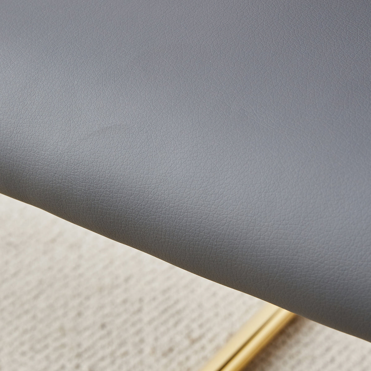 Close-up of gray faux leather upholstery texture on a chair seat cushion.