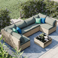 Outdoor sectional patio sofa set with blue-gray cushions, beige wicker frame, and pillows