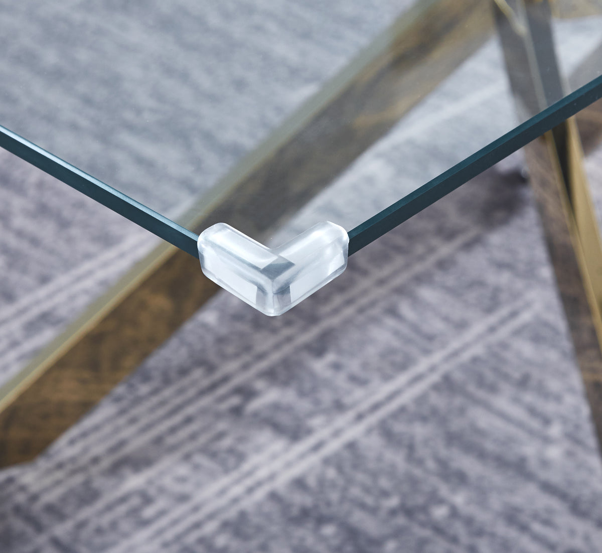 Tempered glass table corner with clear protective cap on the glass edge.