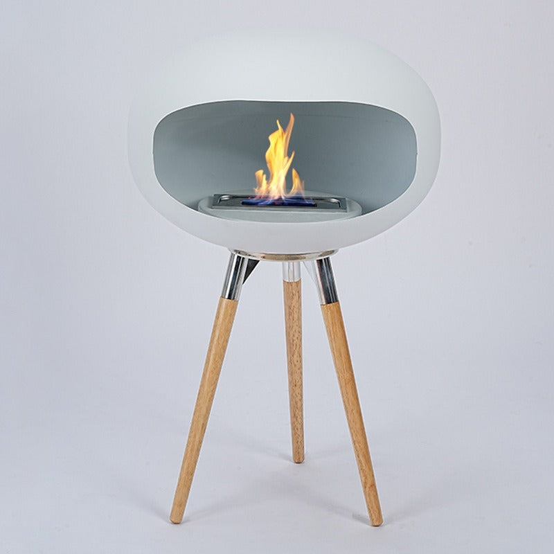 Light gray ethanol fireplace bowl with flame, mounted on three slender wood tripod legs.