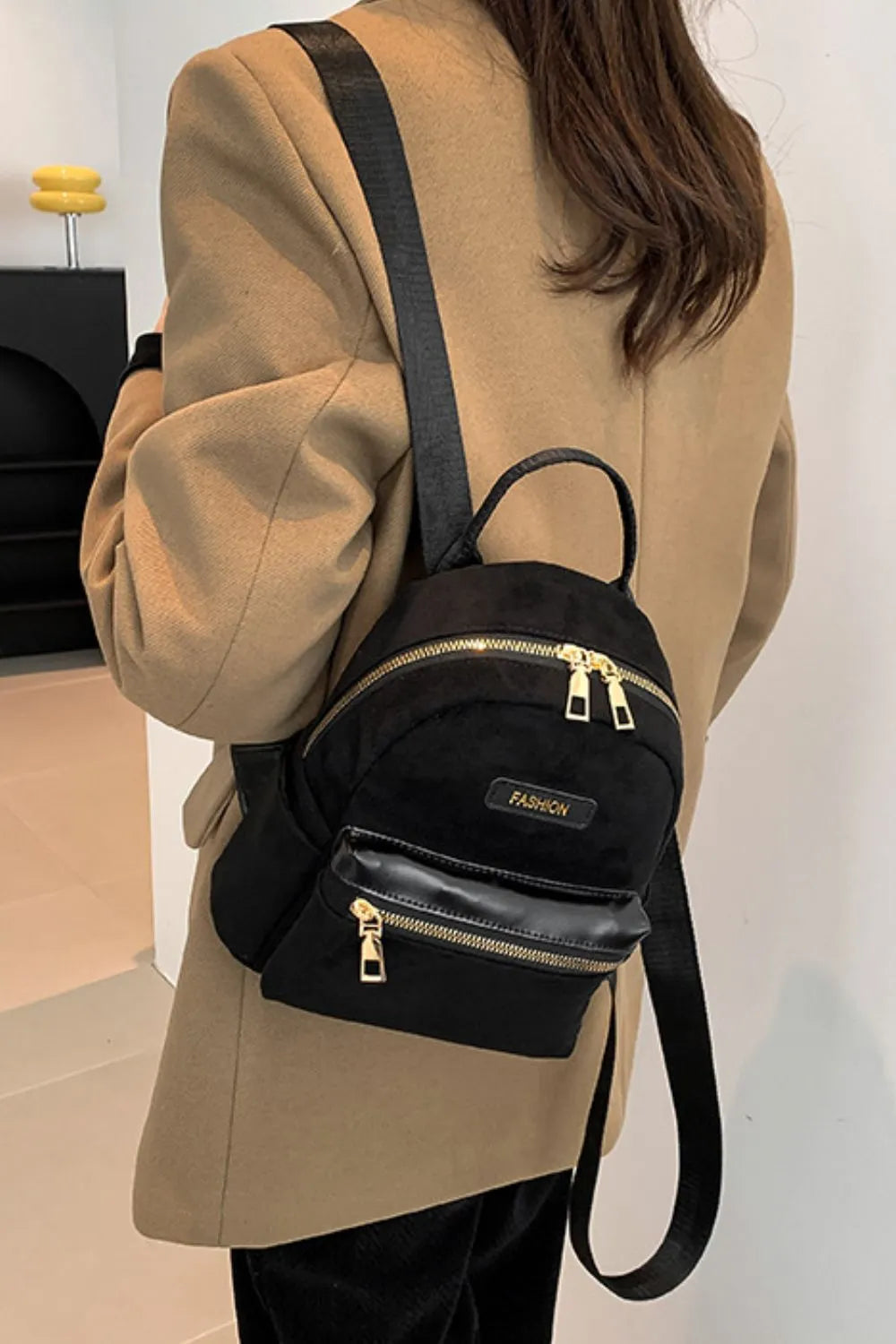 Suede black mini backpack worn on model with front zipper pocket and adjustable strap