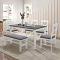 Gray dining table with white chairs and upholstered bench, all with gray seat cushions