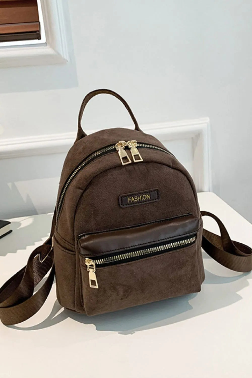 Suede brown mini backpack with dual top handles, adjustable strap, and front zipper