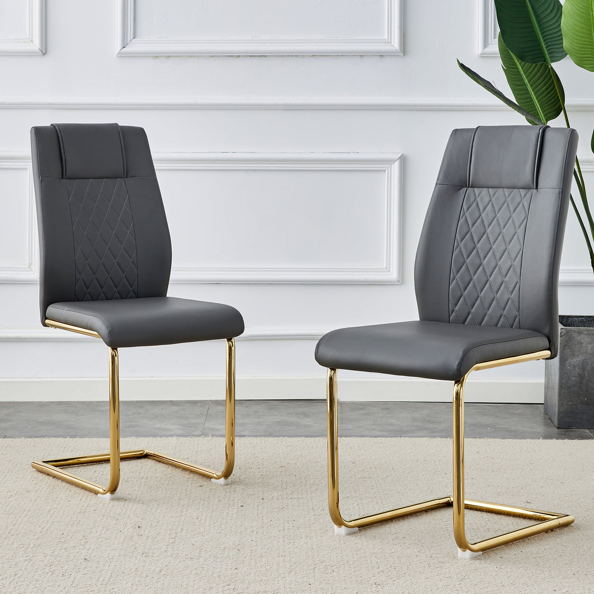 Two gray faux leather chairs with quilted back panels and cushioned seats, gold metal legs.