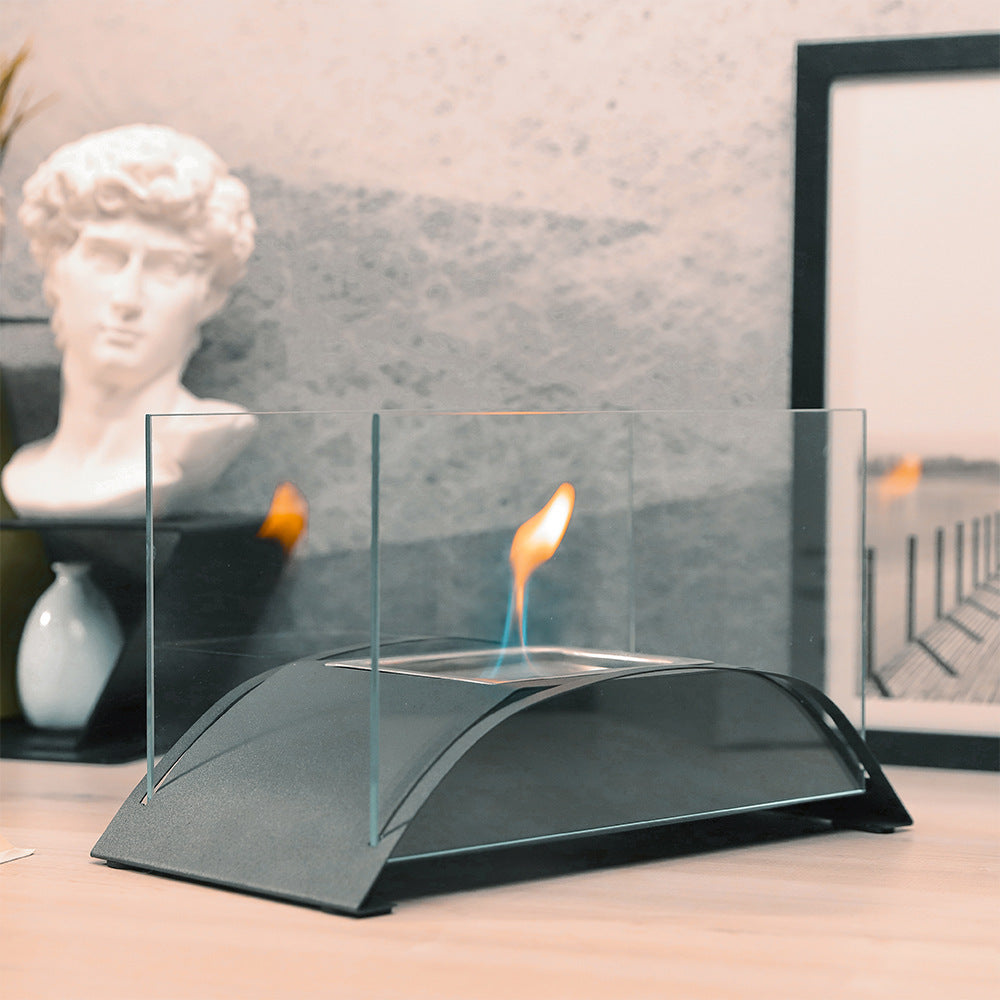 Black tabletop alcohol fireplace with clear glass windscreen and standing flame