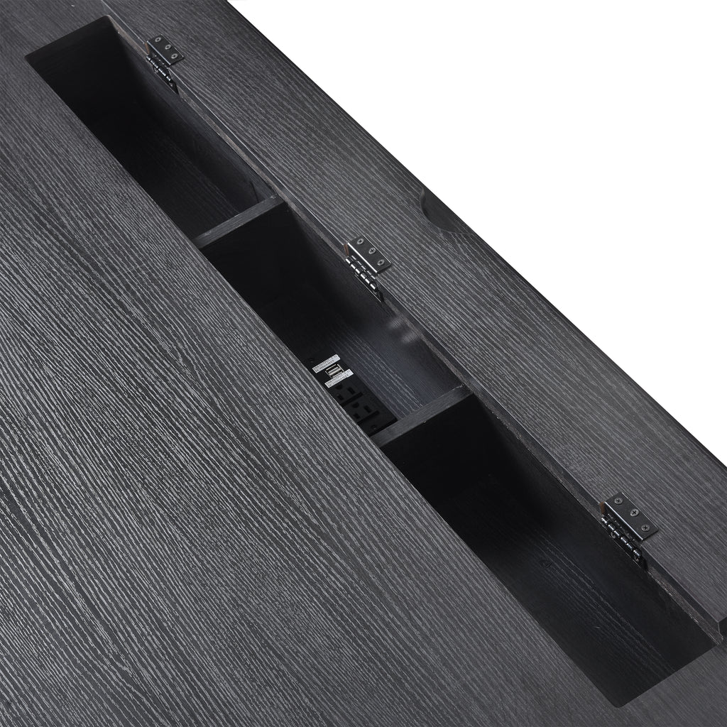 Black desk with open tabletop cable channel and built-in outlet switches inside.