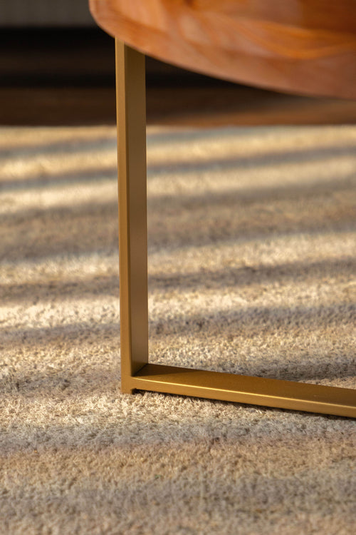 Round coffee table base detail with gold cross legs under the fir wood top