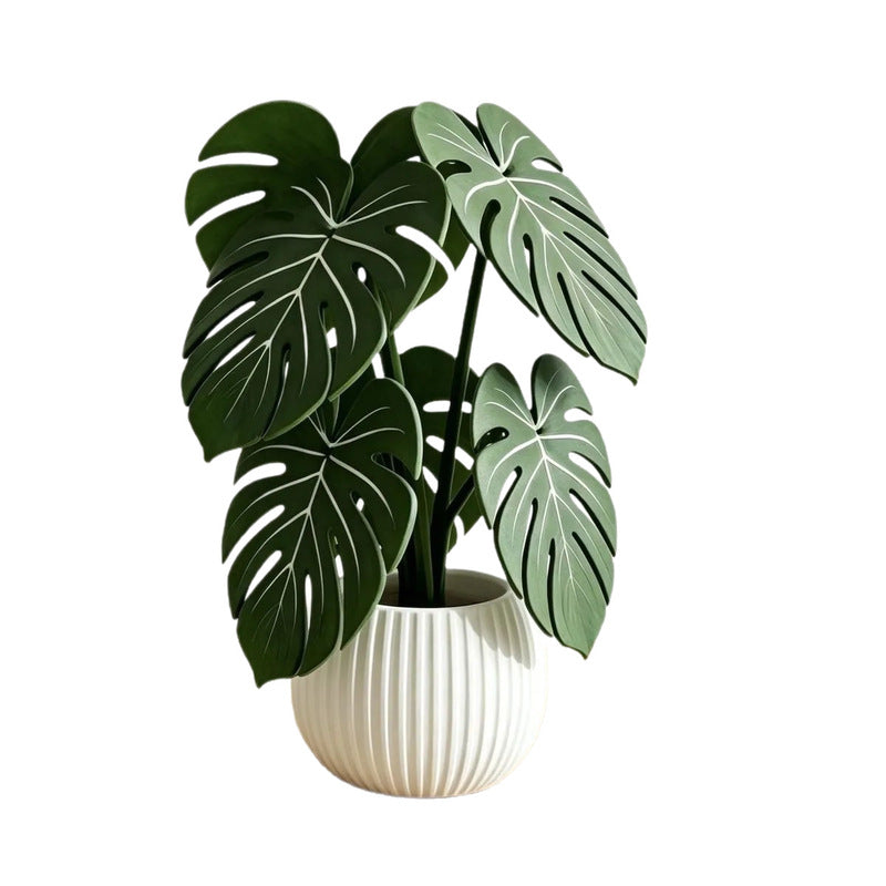 Decorative monstera-leaf plant in a white ribbed pot with green leaf cutouts