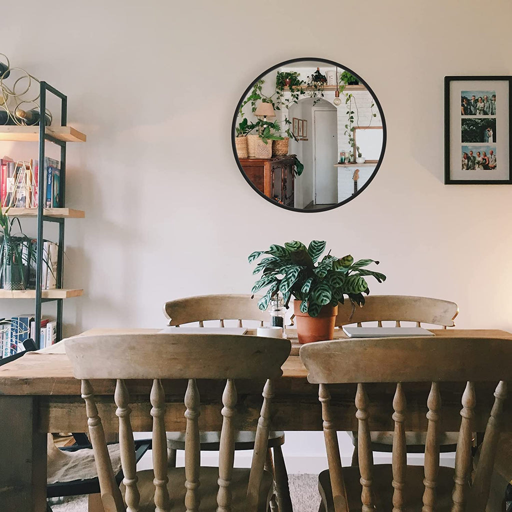 Round wall mirror with black metal frame and reflective glass, indoor scene reflection visible