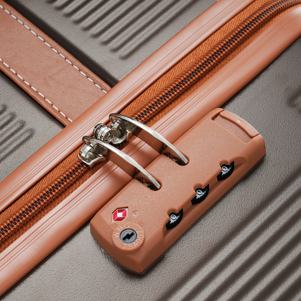 Suitcase TSA lock dial and metal latch on copper-trim corner of ribbed gray shell