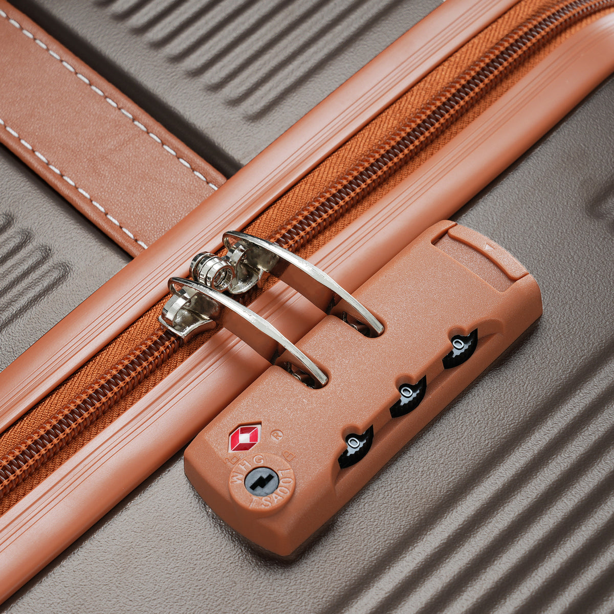 Suitcase TSA lock dial and metal latch on copper-trim corner of ribbed gray shell