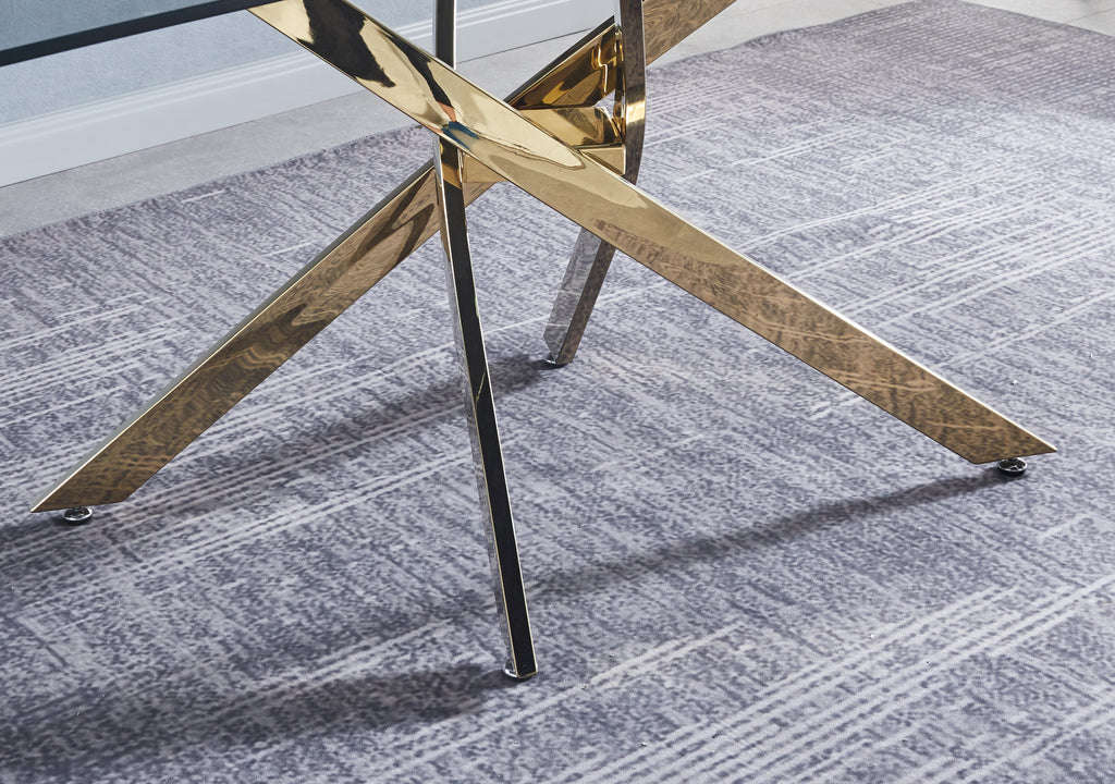 Gold metal X-style table base with black feet beneath the clear glass top.