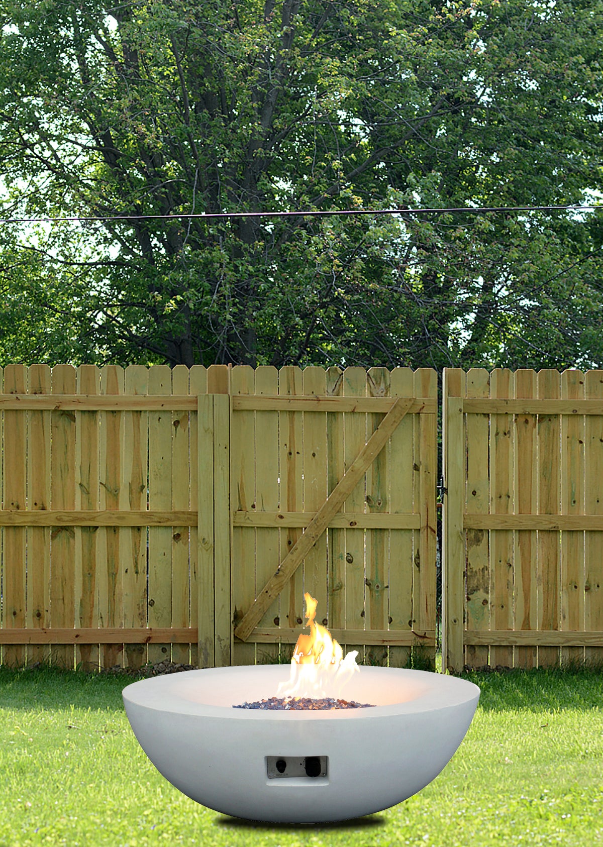Antique white concrete propane fire pit bowl outdoors with flames rising in center
