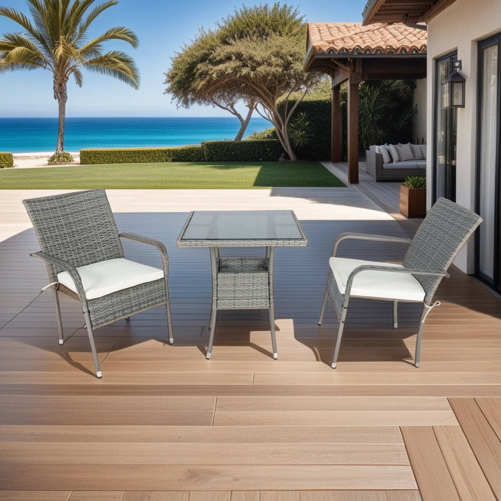 Grey wicker patio conversation set with white cushions and square glass-top table, two chairs.