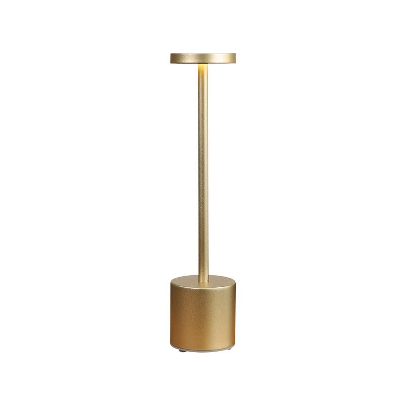 Gold minimalist table lamp with small drum shade and round pedestal base