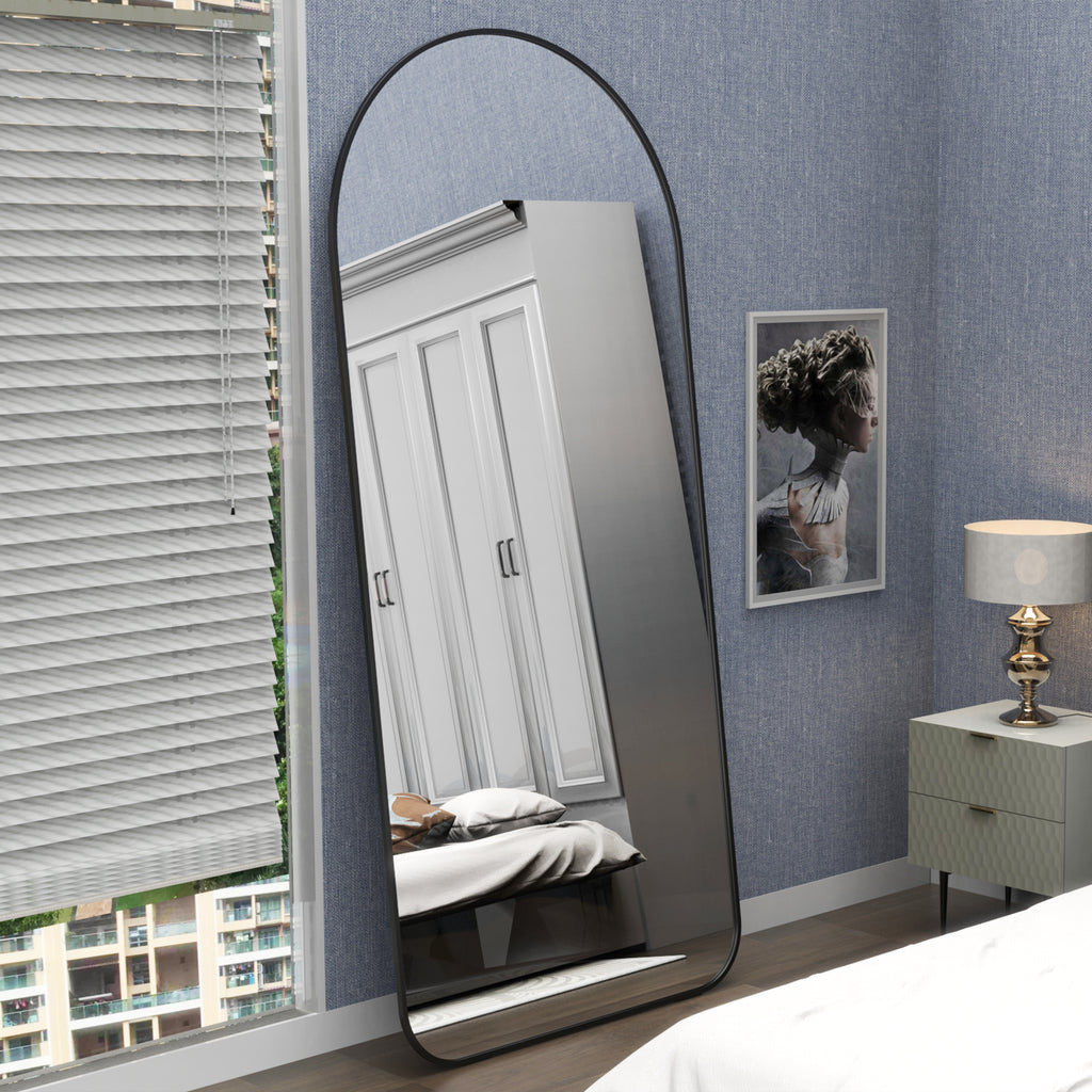 Full-body floor mirror with arched black frame, leaning against wall
